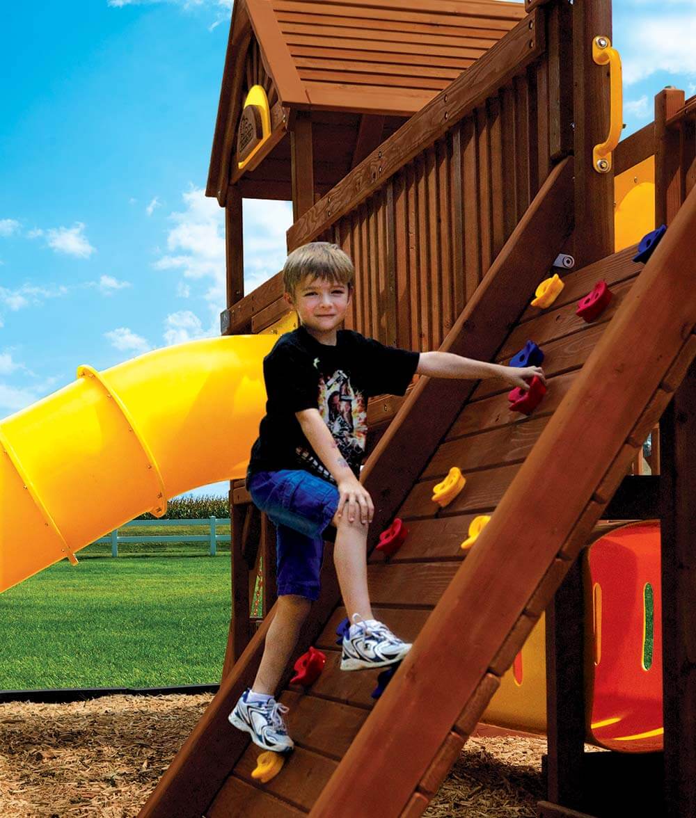 Boy climbing rock wall on a village playset